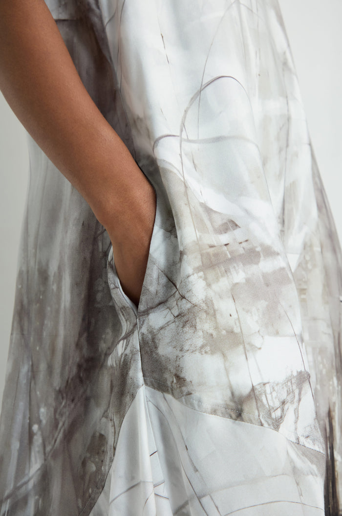 A person wearing the Abstract Print Bubble Dress, featuring a relaxed fit and an abstract light gray and brown pattern, has their right hand in a side pocket.