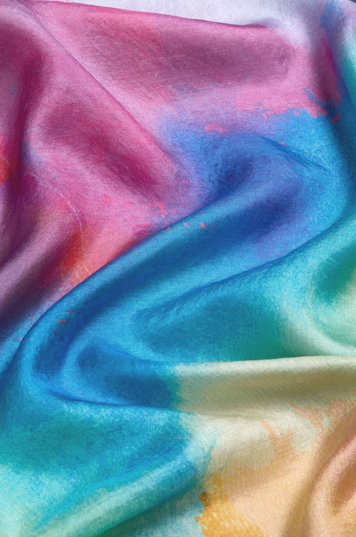 The Aurora Veil Silk Scarf features soft, flowing pure silk adorned with an abstract watercolor print in pink, blue, green, and yellow gradients for an elegant look.