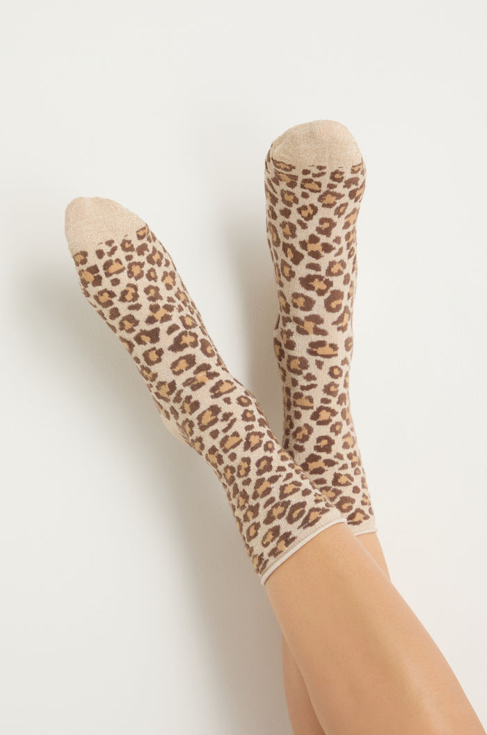 A pair of feet wear Bamboo Leopard Print Socks—beige bamboo-blend with a brown and black leopard pattern—shown against a plain light background.