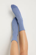 A pair of feet in Bamboo Sparkle Blue Socks, legs extended upward against a plain white background.