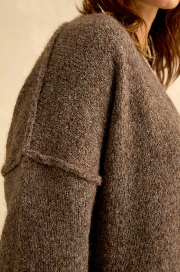 Close-up of a person wearing the Bark Alpaca Blend Long Line Cardigan, its textured brown wool blend and dropped shoulder seams framing their face and neck—an elegant showcase of women’s knitwear classics.