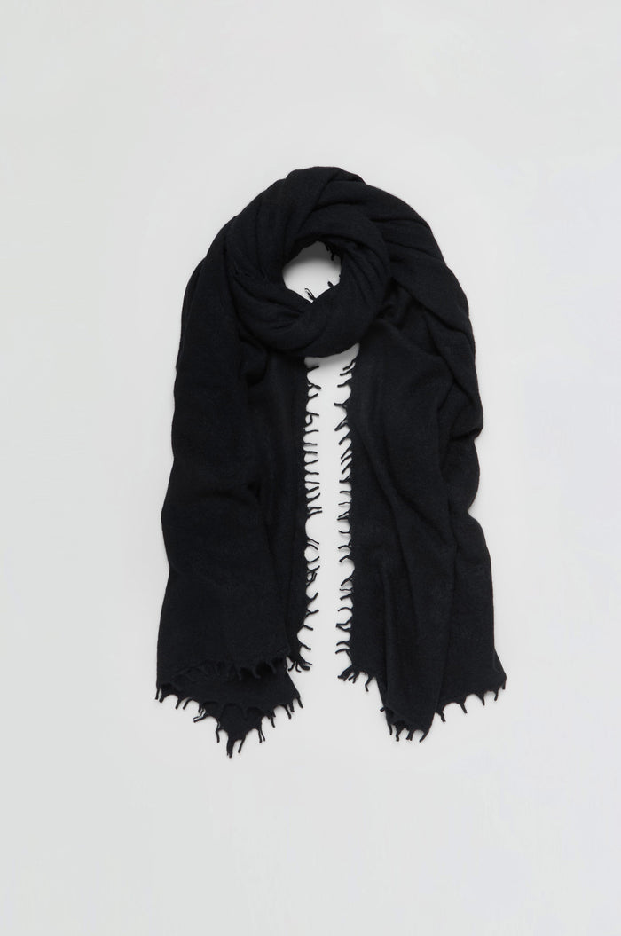 The Black Soft Cashmere Scarf, featuring frayed edges, is loosely folded and displayed against a plain white background.