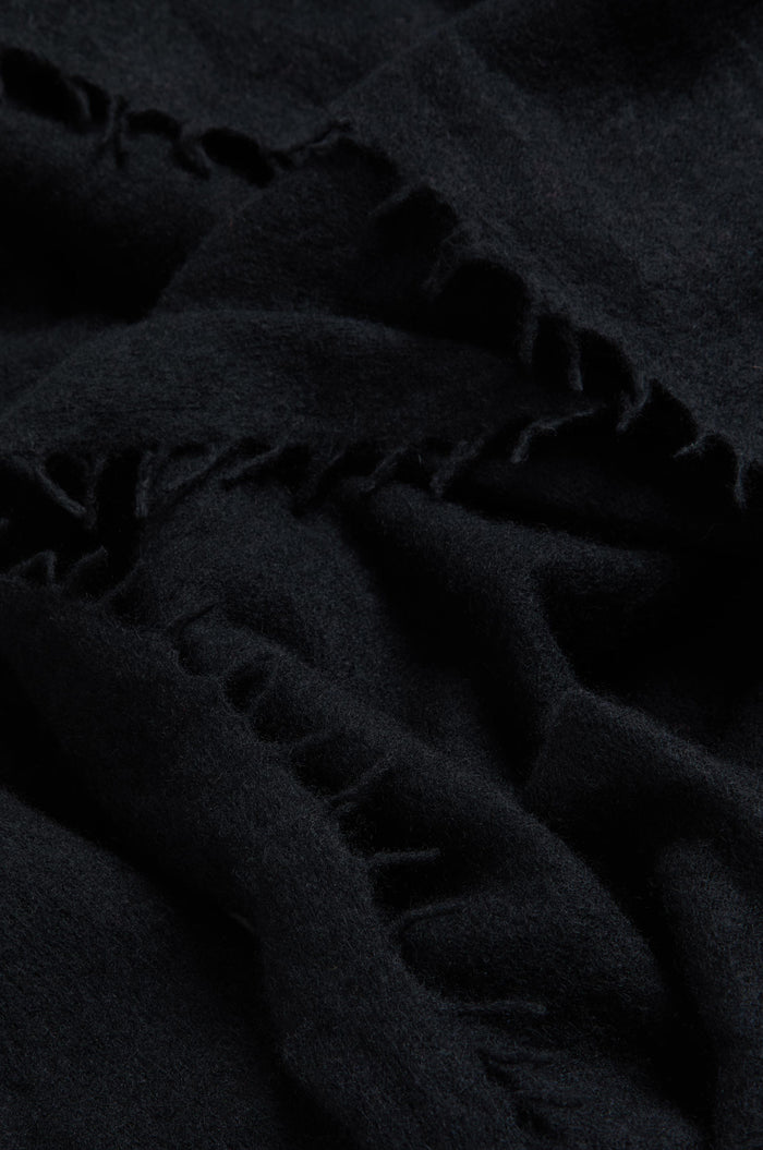 Close-up of the Black Soft Cashmere Scarf, highlighting its dark, luxurious fabric with visible stitching and frayed edges that showcase the soft woven cashmere texture and fine material details.