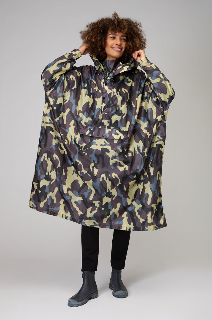 A person models the Camo Poncho with black pants and gray boots, standing against a plain light gray background.