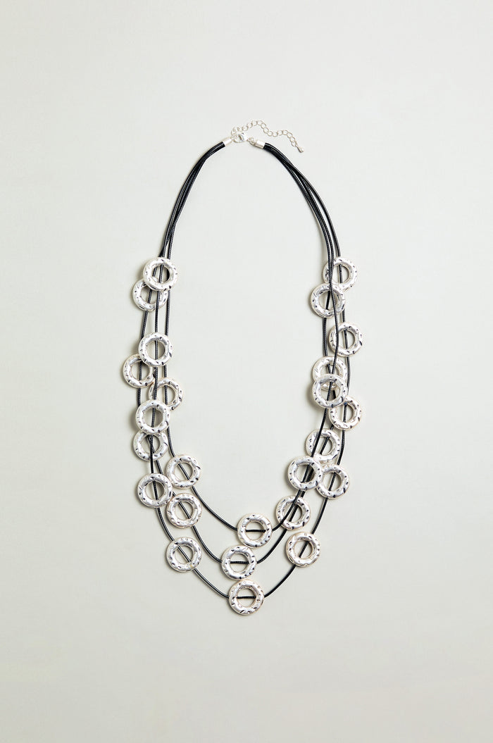 The Cascade Hoops Necklace features three black cords and layered silver textured metal hoops, shown against a plain light background.