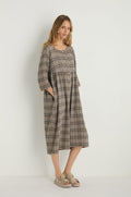 A woman models the Check Button-Through Taupe Dress in plaid textured cotton with three-quarter sleeves and beige sandals, standing against a plain white background.
