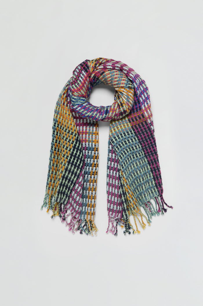 The Checkerboard Scarf features a colorful checkered pattern and fringed ends, crafted from a lightweight wool-blend for timeless style and warmth, displayed flat on a light background.