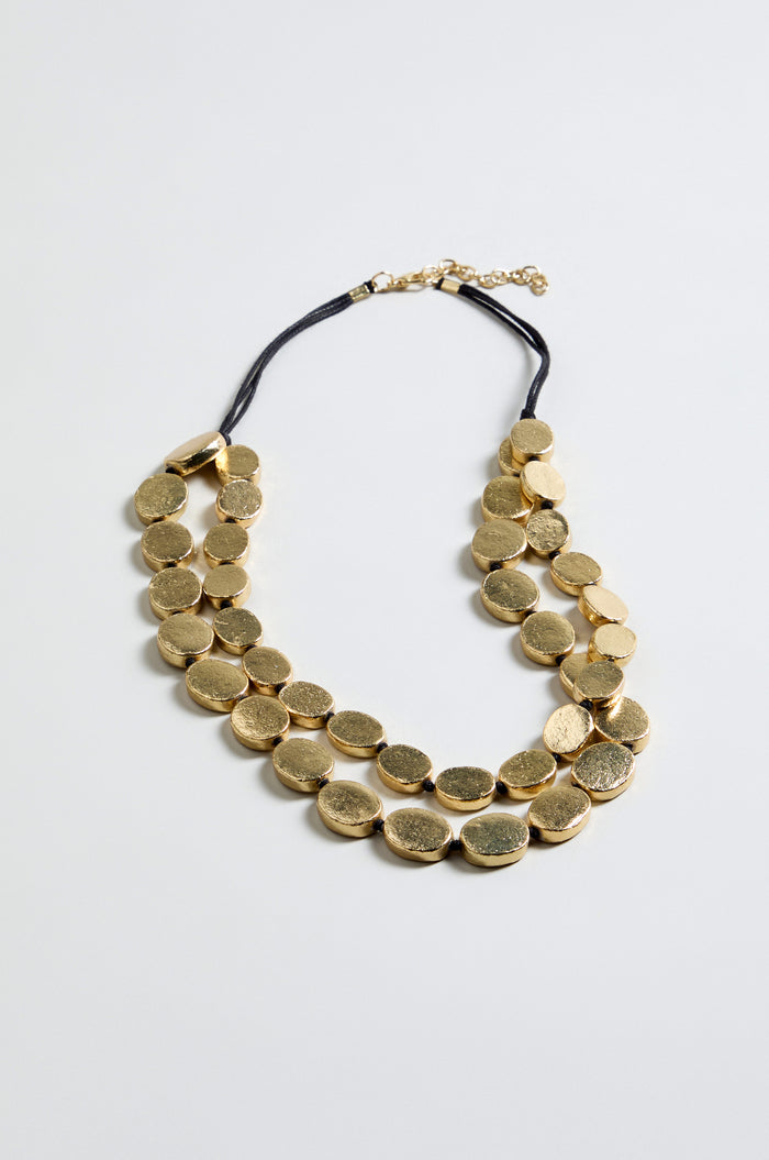 The Double Strand Oval Disc Necklace features two rows of gold-colored, textured oval discs on a black cord with an adjustable clasp, displayed against a plain light background.