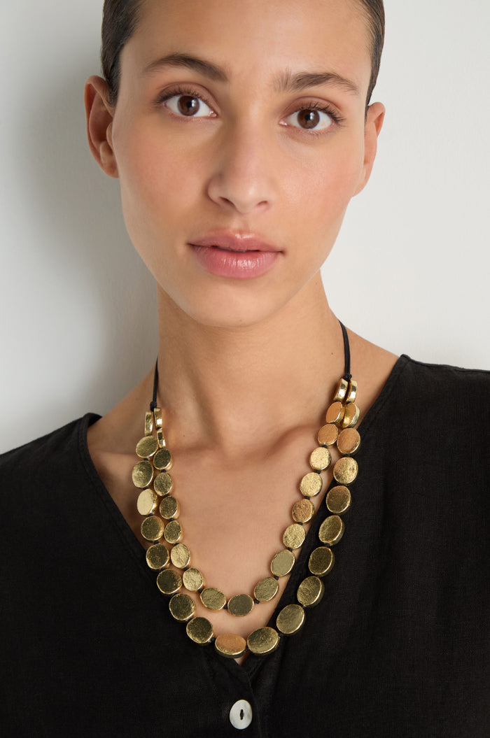 A woman in a black top wears the Double Strand Oval Disc Necklace, featuring oval charms with a textured finish, against a plain white background.