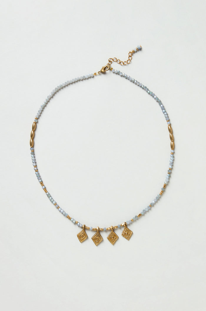 The Eanna Necklace features gold and silver beads, five small gold square charms, faceted cut glass beads, and an adjustable clasp, all displayed on a plain white background.