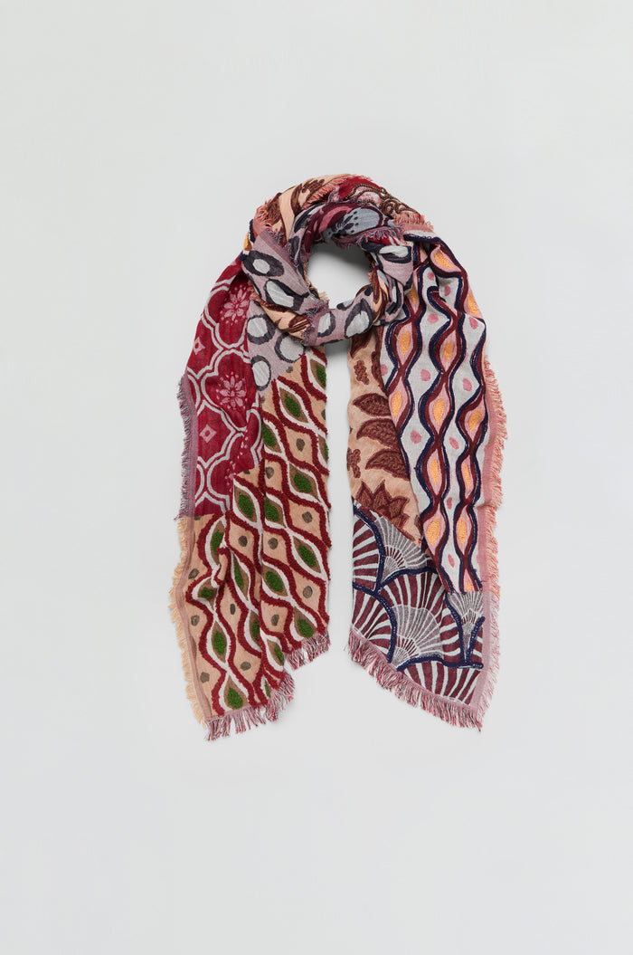 The Embroidered Cotton Wool Scarf is showcased against a plain white background. It features vibrant multicolored geometric floral embroidery on lightweight fabric, finished with fringed edges.