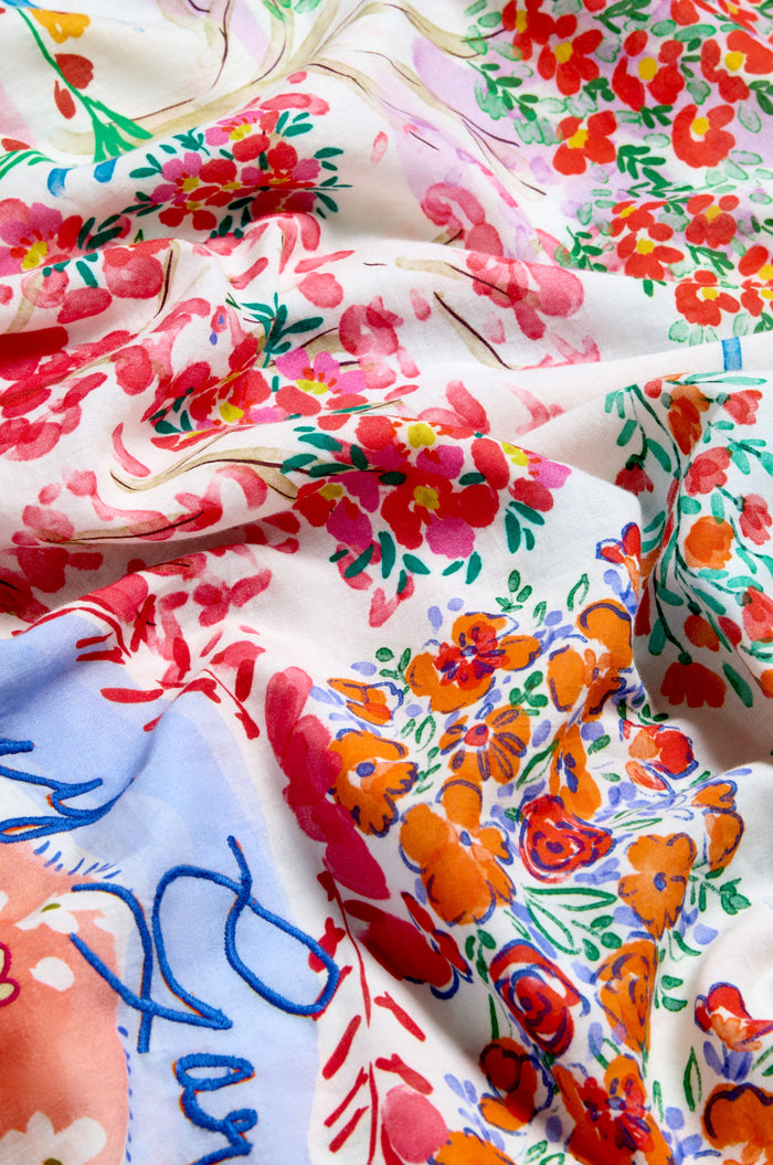 Close-up of the Floral Bouquet Cotton Scarf, showcasing its lightweight cotton fabric and vibrant floral print in red, orange, green, and blue on a white background, with emphasis on the texture and delicate folds.
