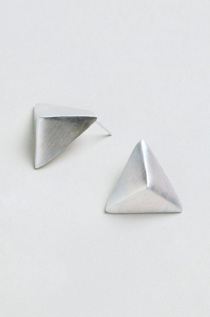 Two Folded Triangle Earrings, silver and pyramid-shaped, are displayed on a plain, light background.
