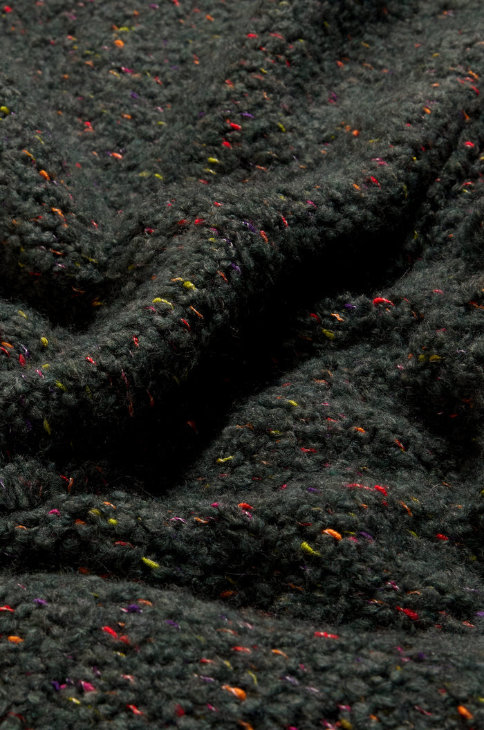 Close-up of the Forest Boucle Knit Long Line Speckle Cardi, featuring a dark, textured boucle knit with colorful specks throughout, highlighting its detailed knit patterns and soft folds.