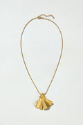 The Gold Vermeil Ginkgo Leaf Pendant features a delicate thin chain and a textured, fan-shaped pendant, displayed on a plain light background.
