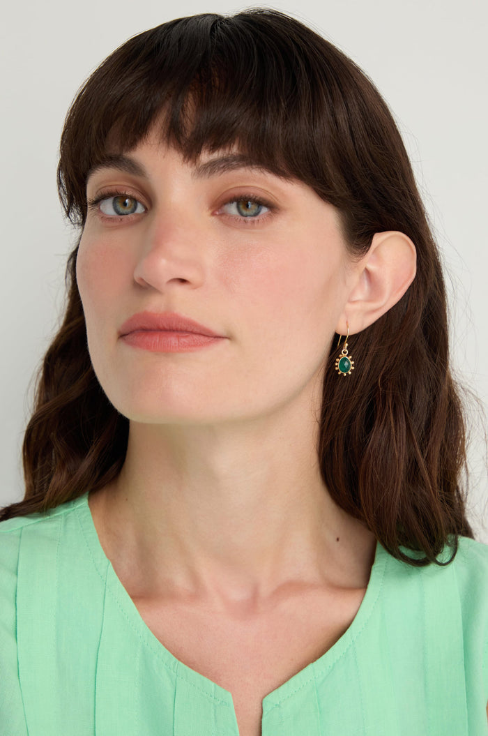 Woman with long brown hair and bangs wears a light green top and Gold Vermeil Green Onyx Earrings, looking directly at the camera with a neutral expression.