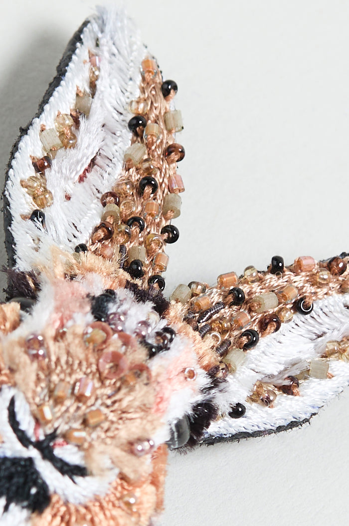 Close-up of the Hand Embroidered Bunny Rabbit Brooch, showcasing a detailed animal ear in white, brown, and black thread, accented with small earth-toned beads.