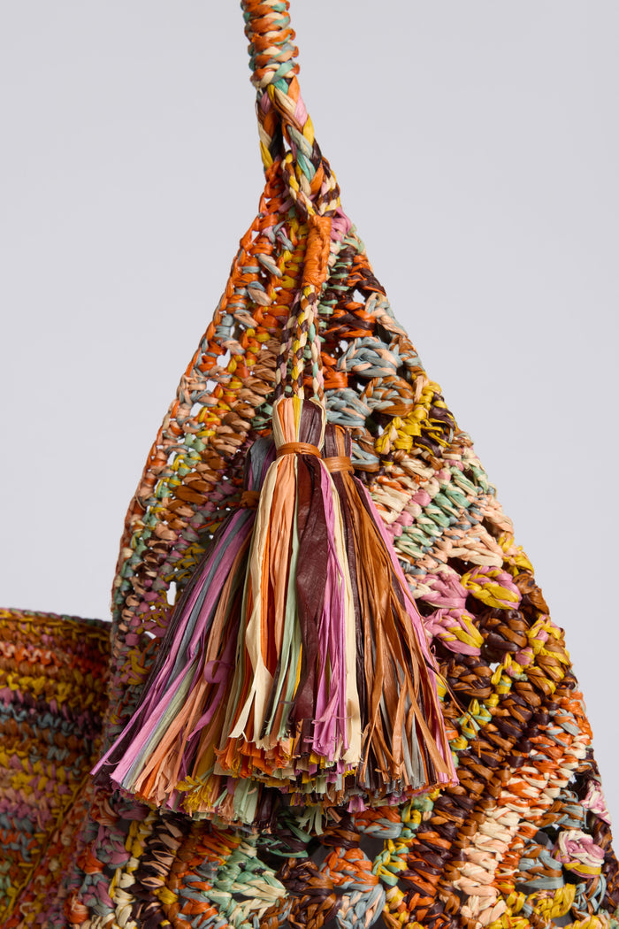 Close-up of the Handwoven Bohemian Raffia Bag, featuring a colorful woven body, braided handle, decorative fiber tassel, and a unique geometric patchwork design.