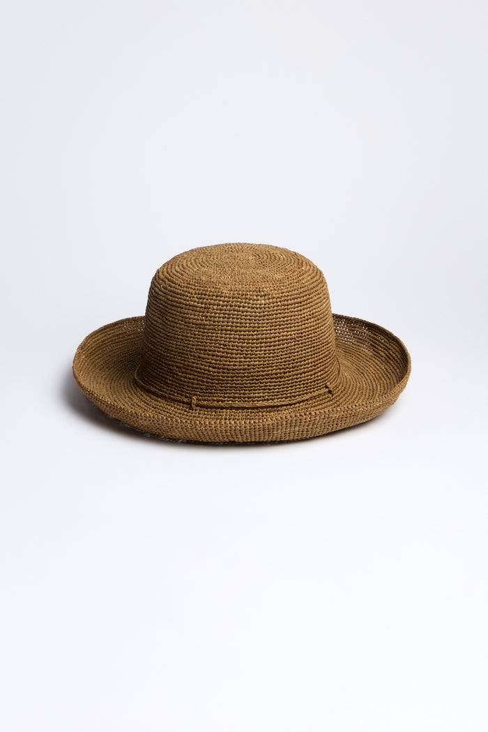 The Handwoven Raffia Hat features a flat crown and wide brim, crafted with Madagascar weaving techniques, set on a neutral background.