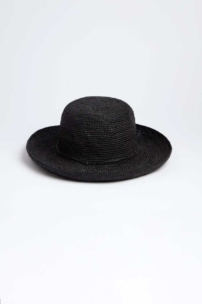 The Rabarany Handwoven Raffia Hat is a black straw hat with a wide brim and rounded crown, expertly crafted using Madagascar weaving techniques. Displayed on a plain white background, it highlights its lightweight and breathable design.