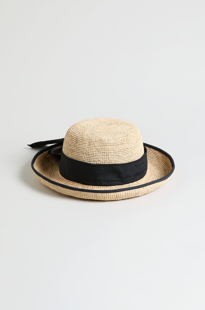 The Handwoven Raffia Ribbon Hat features a wide black ribbon band and bow, expertly crafted with a wide brim and displayed against a plain light background.