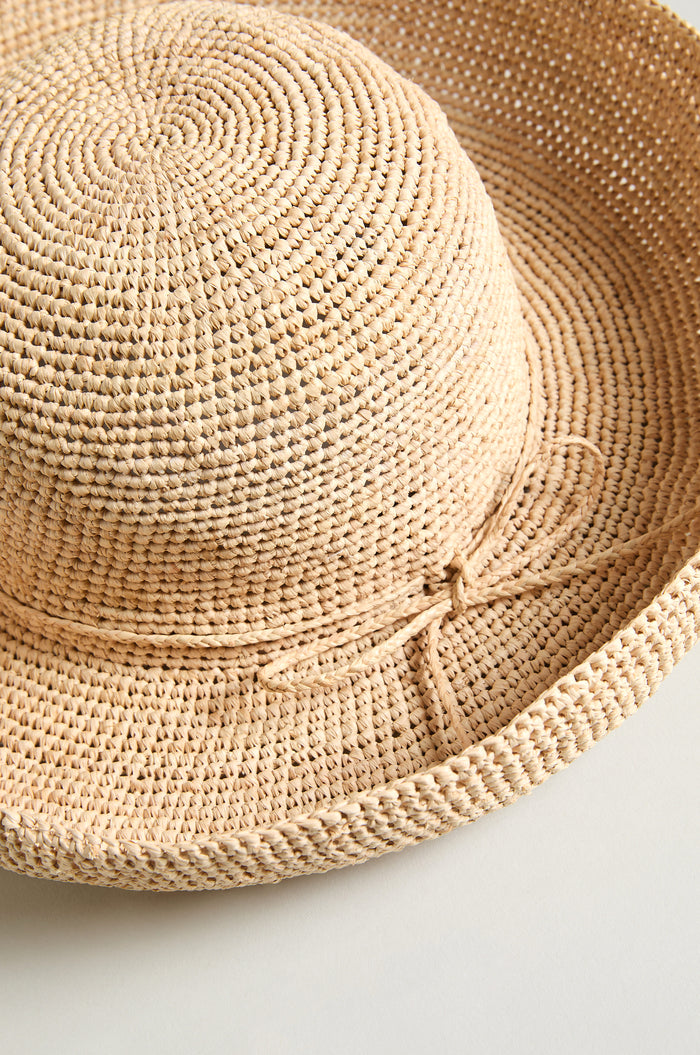 The Handwoven Raffia Tie Hat features a wide brim and a simple bow, making it perfect for sunny days.