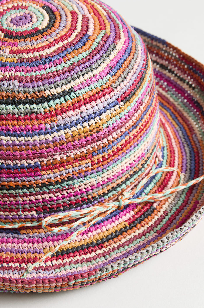 Close-up of the Handwoven Rainbow Raffia Hat, featuring vibrant stripes and a matching bow at the crown's base, skillfully crafted by artisans in Madagascar.