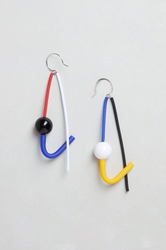 The Kandinsky Sphere Earrings feature bent tubes in red, blue, white, yellow, and black with round beads. Handmade in Paris, these abstract sculptural earrings are showcased on a light background.