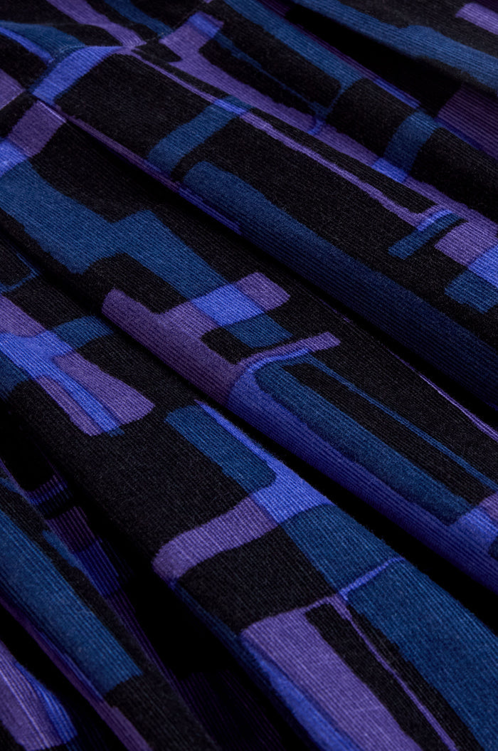 Close-up of folded fabric featuring an abstract geometric pattern in shades of blue, purple, and black—ideal for the Layered Geometric Cord Flared Dress.