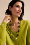 Woman wearing a lime green sweater and the Long Allsorts Necklace—a long resin necklace with black, silver, and brown beads—looking off to the side with a neutral expression.