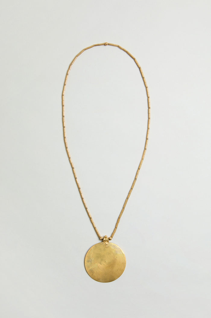 The Long Spiral Pendant features a thin, beaded gold chain with a large, round spiral pendant—ideal for making a statement. Displayed on a light, neutral background.