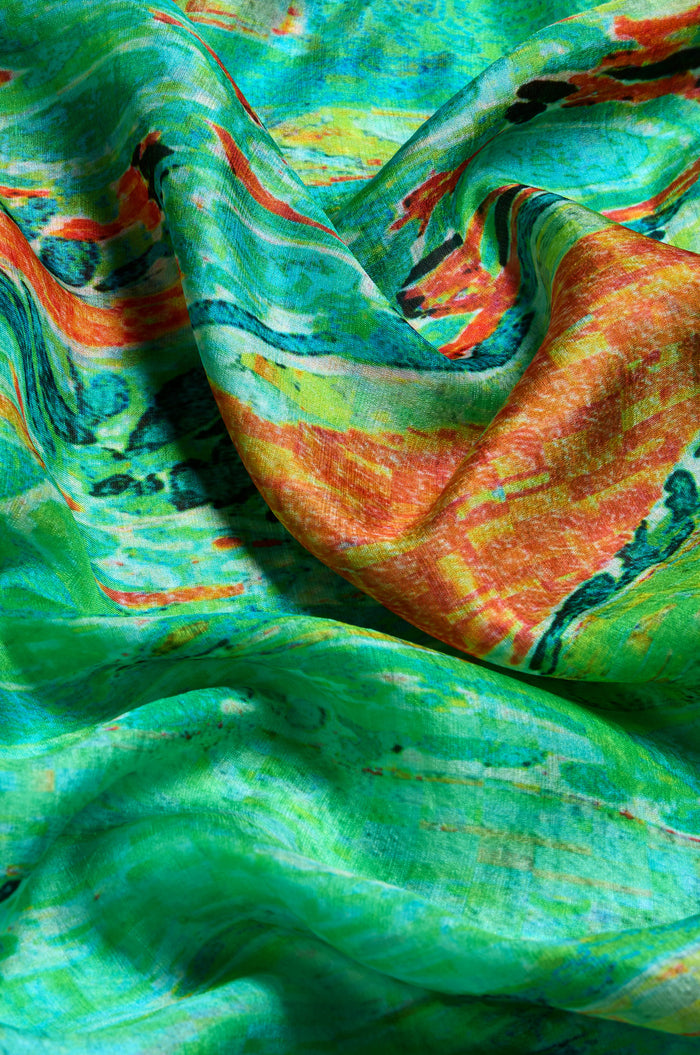 Close-up of the Meadow Silk Scarf, made from pure silk, featuring green, orange, yellow, and black abstract prints. The scarf is softly draped and lightly wrinkled.