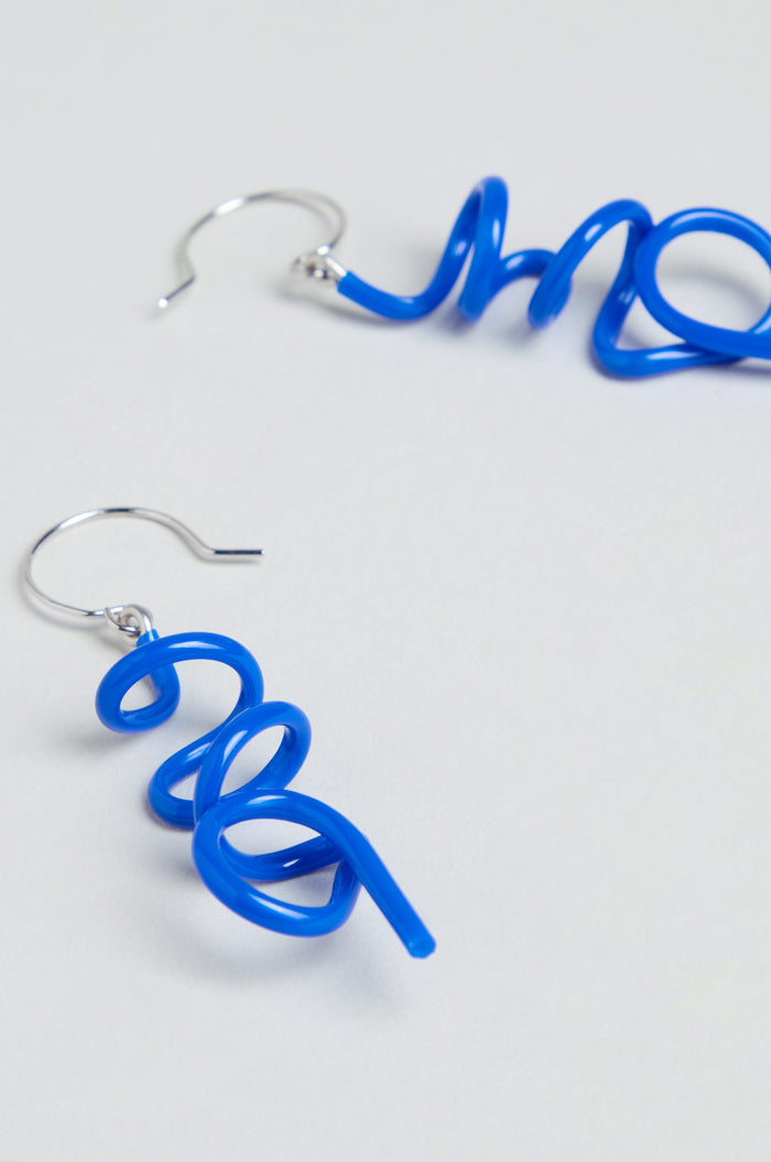 Handmade in Paris, the Mini Sketch Earrings feature blue plastic twisted into spirals with silver hooks and are shown on a simple light background.