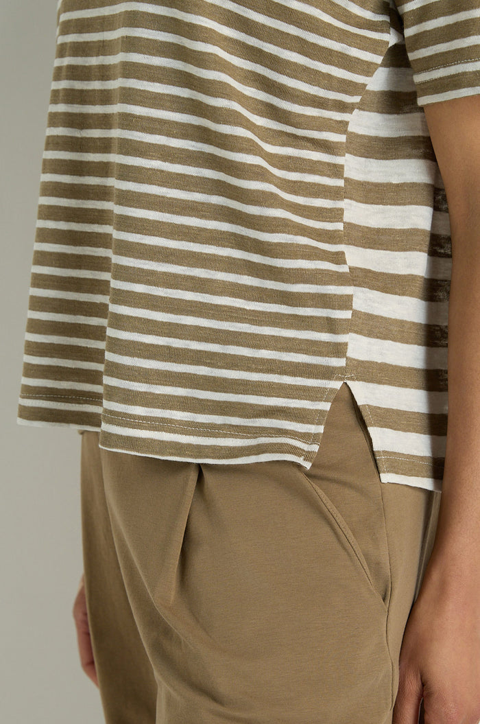 A person is shown from torso to mid-thigh wearing the Mixed Stripe T-Shirt in brown and white stripes with a side slit, paired with tan pants.