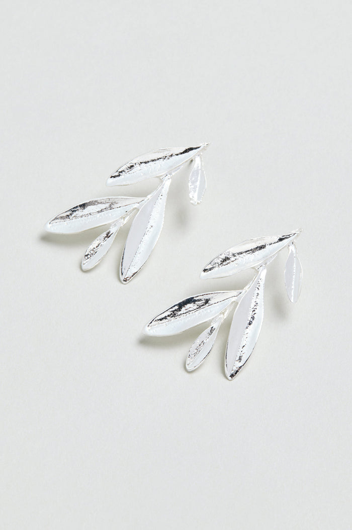 Introducing the Olive Branch Earrings: a pair of elegant silver plated drop earrings with a graceful design featuring three elongated leaves and one small leaf on each earring, beautifully displayed against a light background.