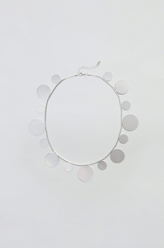 Introducing the Orbit Disc Necklace—a stylish accessory featuring circular silver disc charms evenly spaced along the chain, beautifully presented against a plain white background.