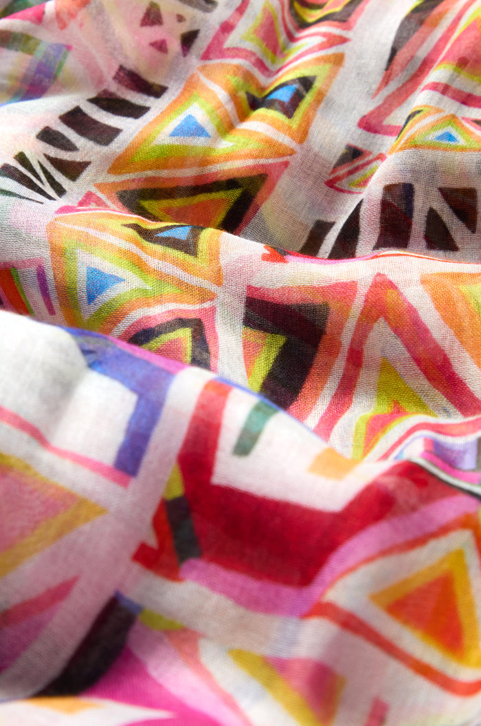 Close-up of the Painted Geometric Scarf, featuring vibrant triangles and lines in yellow, red, pink, green, blue, and black on soft, lightweight fabric with a luxe feel and a slightly wrinkled texture.