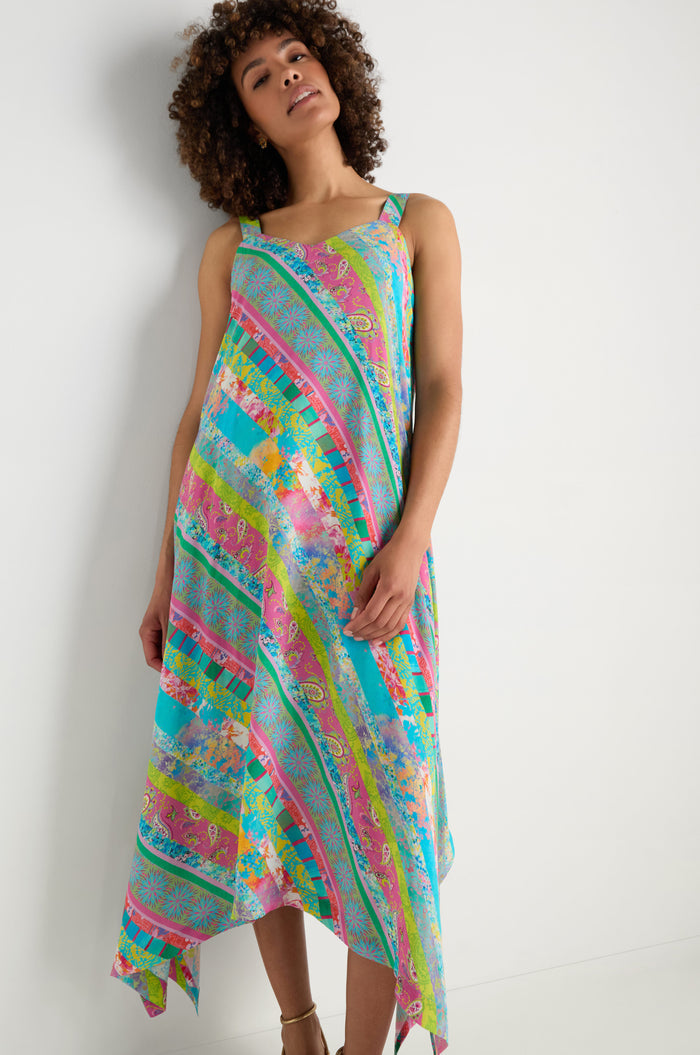 A woman models the Patchwork Stripe Summer Dress, a colorful, sleeveless dress made from soft viscose crepe, shown against a white background—ideal for summer.