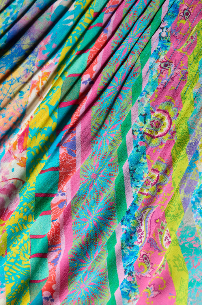 The Patchwork Stripe Summer Dress features colorful diagonal stripes with floral and paisley patterns in vibrant pink, green, blue, yellow, and red tones.