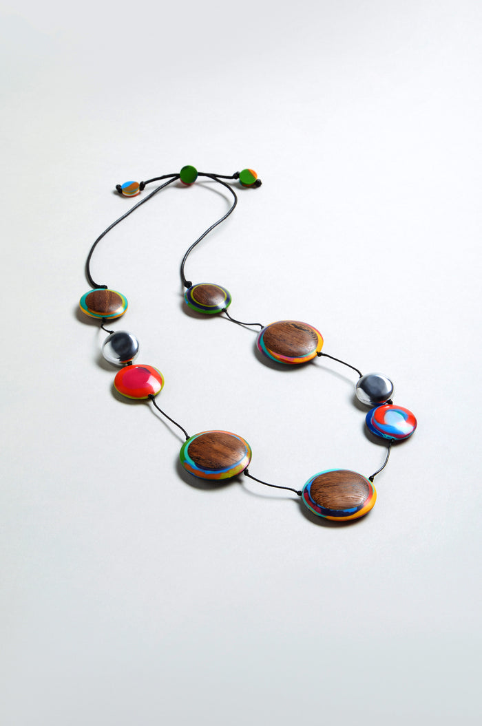 The Planetary Necklace features large round wood and multicolour resin beads on a black cord, displayed against a light gray background.