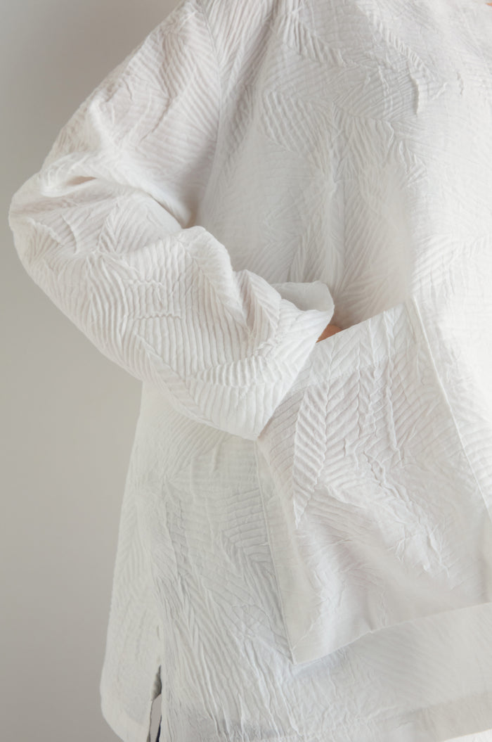 Model wearing the Pleated Leaf Short Jacket with hand partly tucked into the large front pocket; only torso and arm are shown.