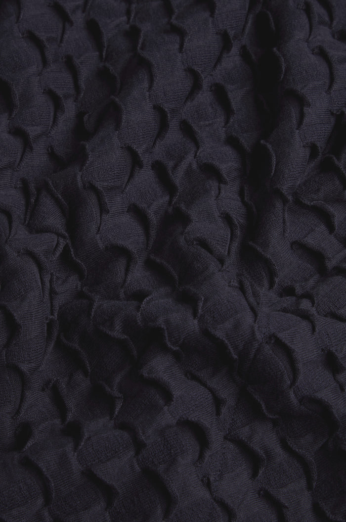 Close-up of dark, textured fabric with an embossed, scallop-like pattern and visible folds—perfect for a sophisticated Pocket Jersey Tube Skirt.