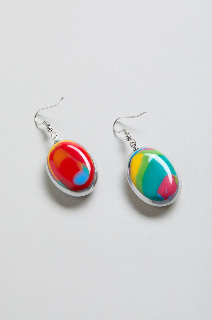 Rainbow Pebble Earrings are oval-shaped, made from multicolour resin with abstract red, yellow, green, and blue patterns, shown on a light background.