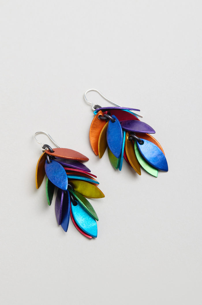 The Scattered Leaves Earrings showcase layered leaf-shaped anodised aluminium in metallic blue, green, yellow, purple, and orange, creating lightweight drop earrings that add vibrant movement to any look.