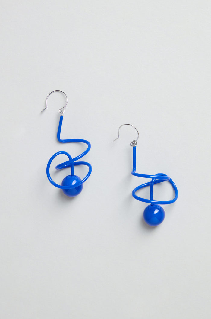 The Scribble Sphere Earrings are handmade in Paris, featuring blue twisted wire with a sculptural design and a spherical bead, shown on a plain light background.