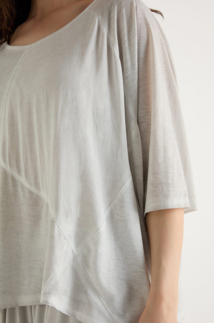 A person wearing the Seam Detail Jersey Top—a loose-fitting, light gray viscose jersey with a round neckline and relaxed silhouette—shown from shoulders to hip.