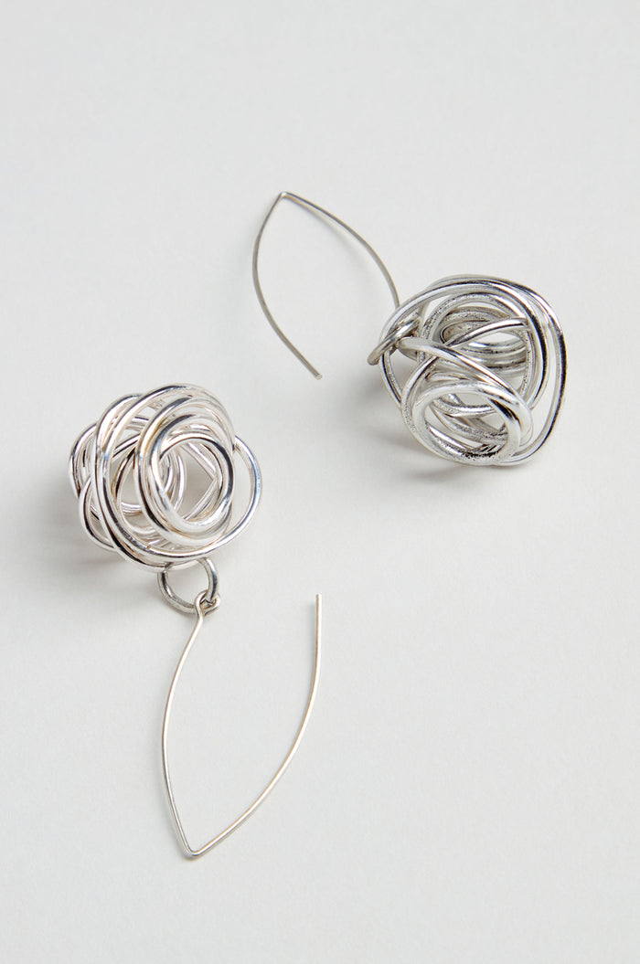 The Silver Scribble Earrings feature a unique tangled knot design with curved, thin wire hooks for a sculptural look that’s lightweight and stylish.
