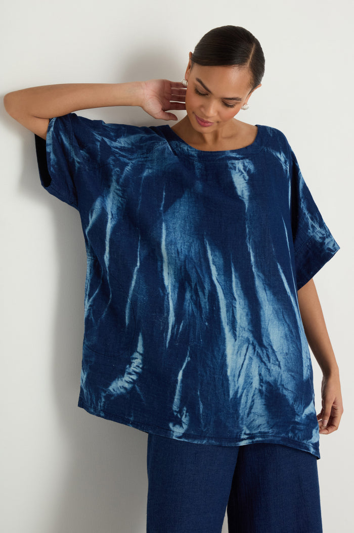 A woman models the Soft Denim Button-Back Tunic with matching blue pants, featuring a longline silhouette, against a plain light backdrop.