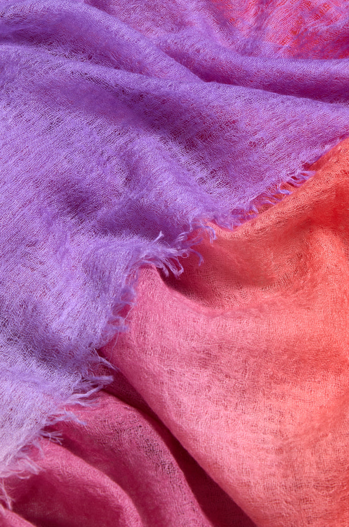 Close-up of the St. Tropez Cashmere Shawl, featuring a soft, textured knit and a gradient from purple to pink and coral—ideal for lightweight layering in St Tropez.