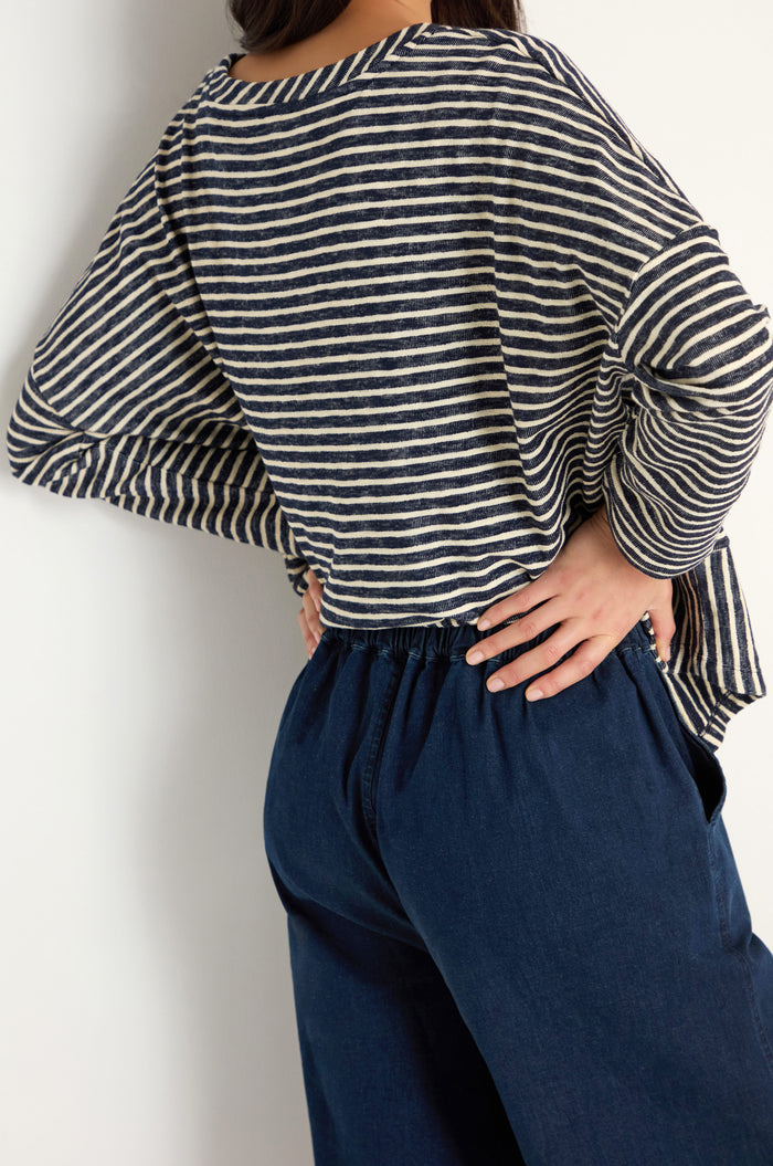 Person wearing a navy and white striped long-sleeve shirt and high-waisted Stretch Denim Bubble Trouser with a relaxed fit, standing with one hand on their hip against a white background.